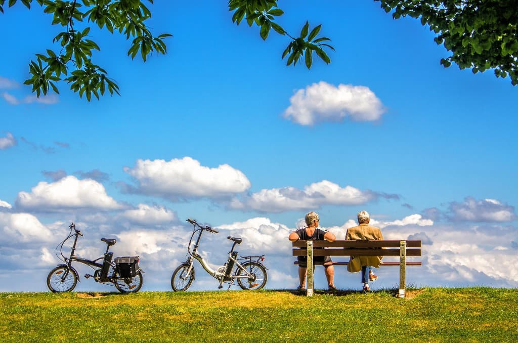 Deux personnes âgées sur un banc face au paysage, vélos à proximité